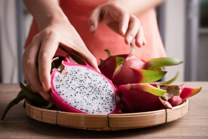 Une personne servant des tranches de fruits du dragon au petit-déjeuner.