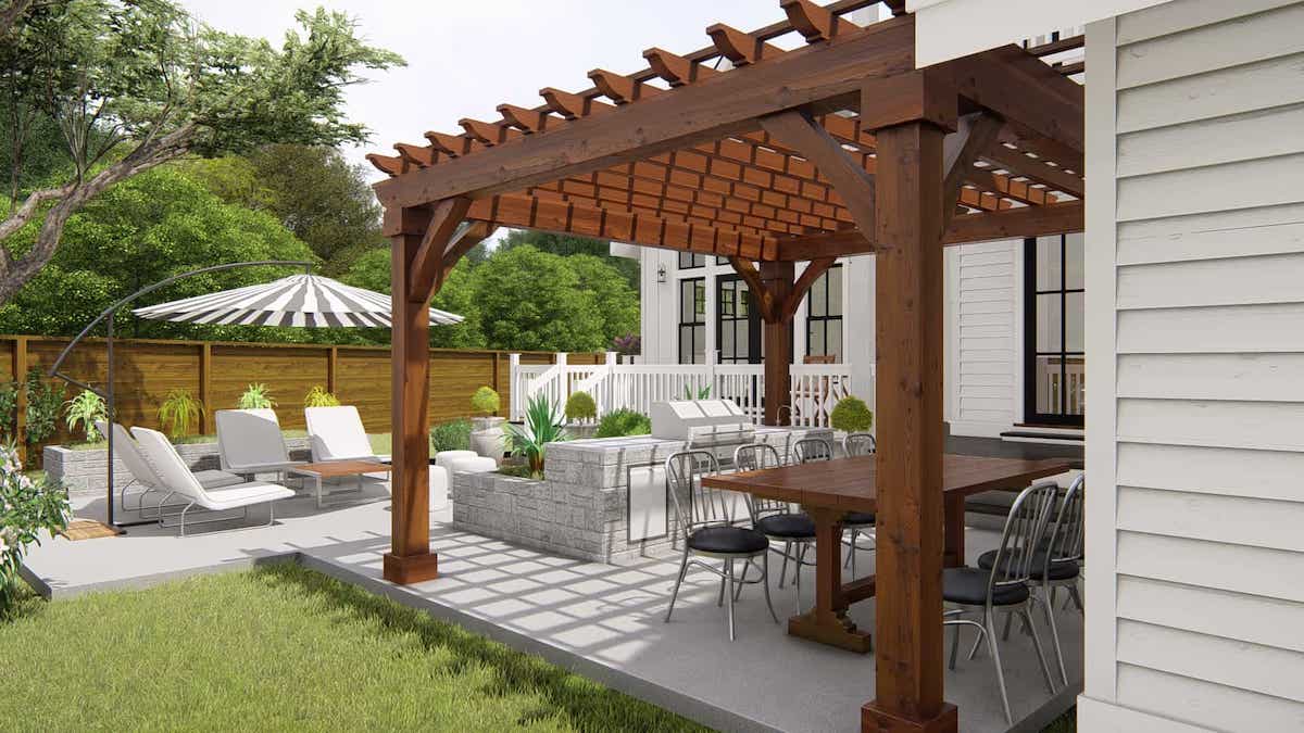 Les meubles de jardin d'un patio se trouvent sous une pergola en bois fixée sur le côté d'une maison blanche.