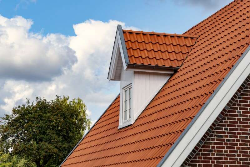 Le toit d'une maison en briques est recouvert de bardeaux de couleur terre cuite de style méditerranéen.