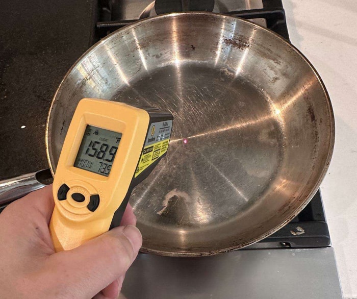 Personne utilisant le pistolet IR ThermoWorks pour mesurer la température de surface d'une casserole en acier inoxydable