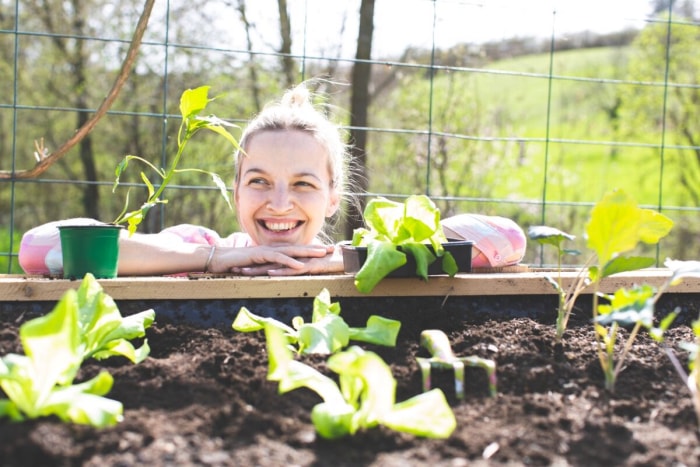 Femme souriant autour de plantes dans un jardin surélevé