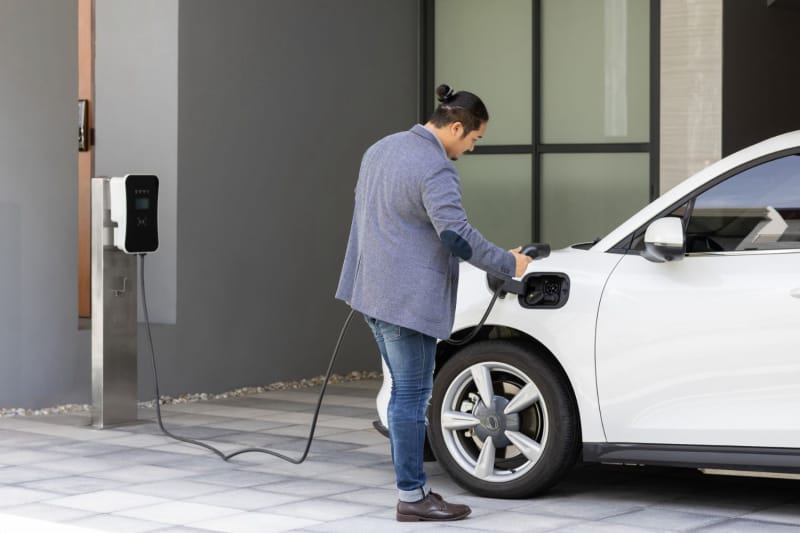 Un homme recharge son EV à l'extérieur d'une maison moderne.