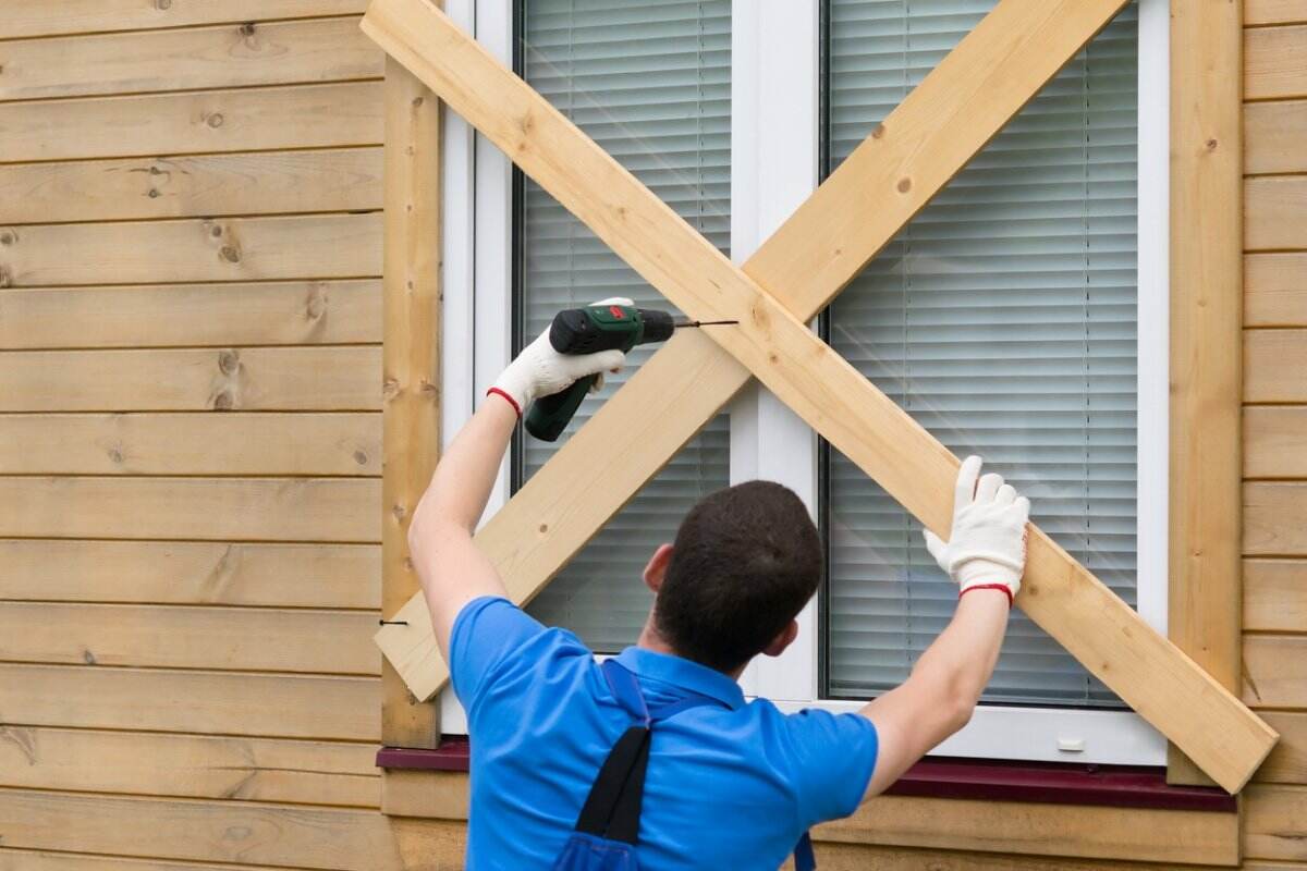 Une personne bloque une fenêtre d’une maison. 