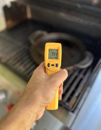 Personne prenant la température intérieure du gril avec un pistolet IR Thermoworks jaune