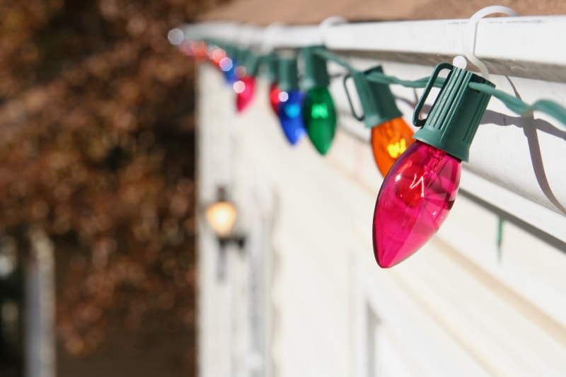 Gros plan des lumières de Noël sur le toit d'une maison, maintenues en place par des clips en plastique.