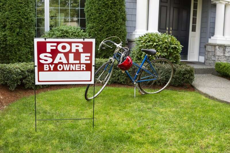 panneau à vendre par le propriétaire devant la maison avec vélo dans la cour avant