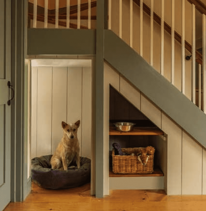 escalier avec revêtement vert avec un coin pour un chien qui s'assoit sur un lit pour chien et une étagère avec des jouets pour chiens