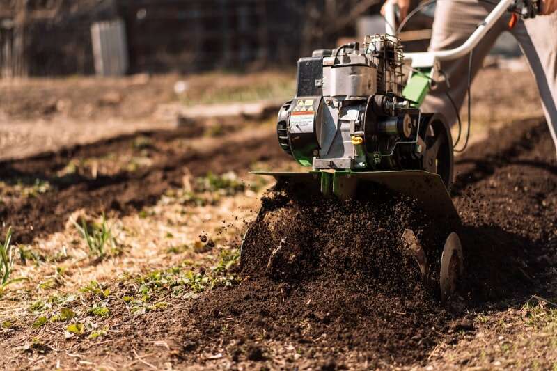 Cultivateur de jardin vert broyant le sol du jardin.