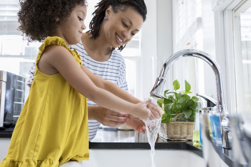 mère et fille se lavant les mains à l'évier de la cuisine en utilisant un robinet à faible débit