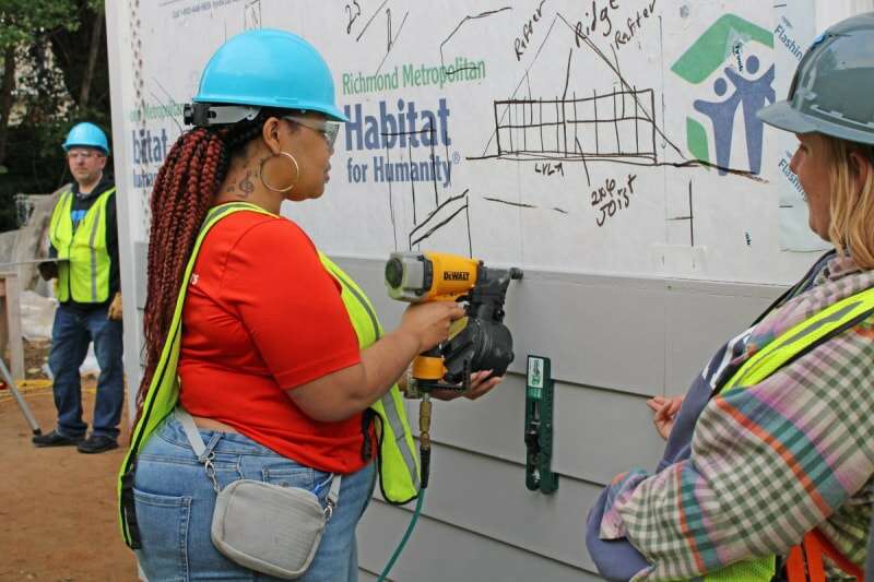 Une femme portant un casque de protection utilise un outil électrique lors d'une construction d'Habitat for Humanity Pride à Richmond.