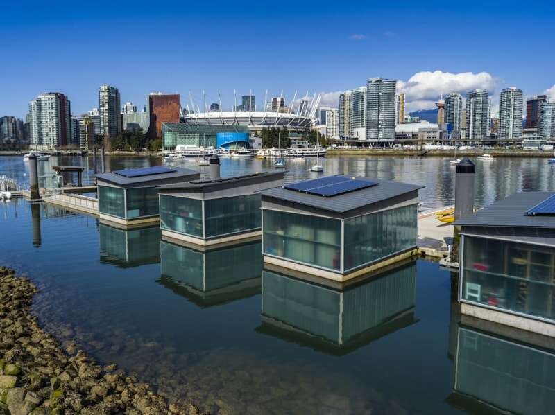 Quatre maisons flottantes sont alignées le long de la ligne d'horizon de Vancouver, au Canada.