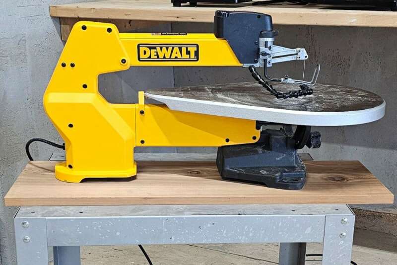 La scie à chantourner DeWalt sur une petite table de travail avec une surface de travail poussiéreuse après le test.