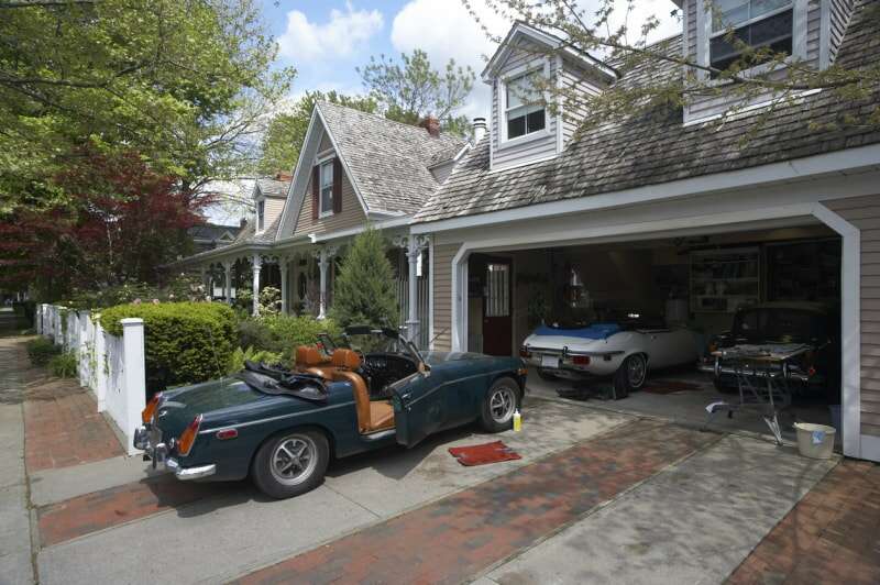 Maison de campagne avec garage contenant trois voitures anciennes.