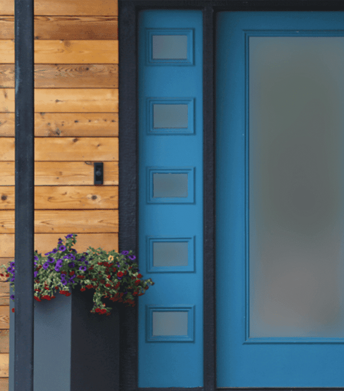 Porte d'entrée moderne de couleur bleue avec fenêtre en verre et fenêtres latérales, le tout avec un film de protection de la vie privée.