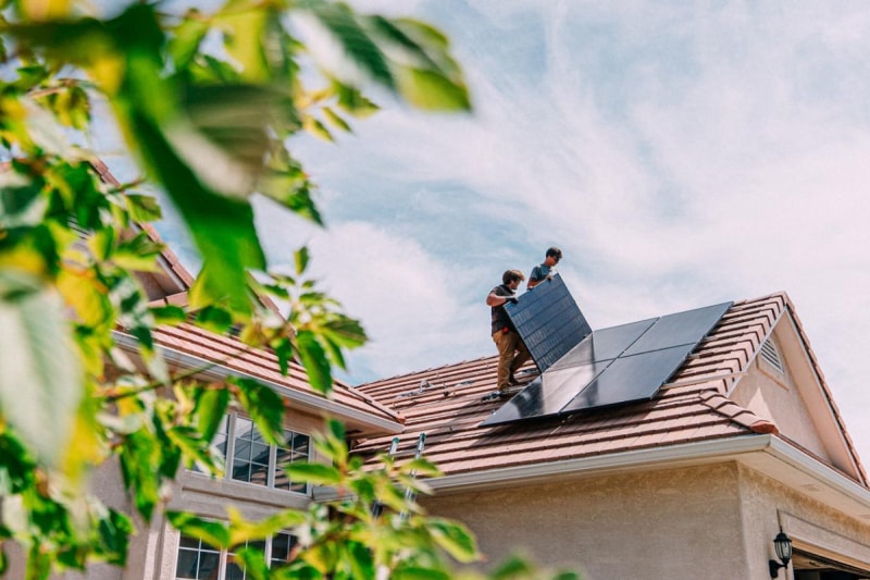 Vue de deux ouvriers installant des panneaux solaires sur un toit. 