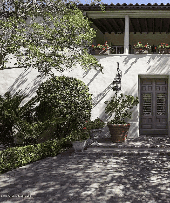 L'entrée d'une maison de style espagnol se trouve au bout d'une cour ombragée.