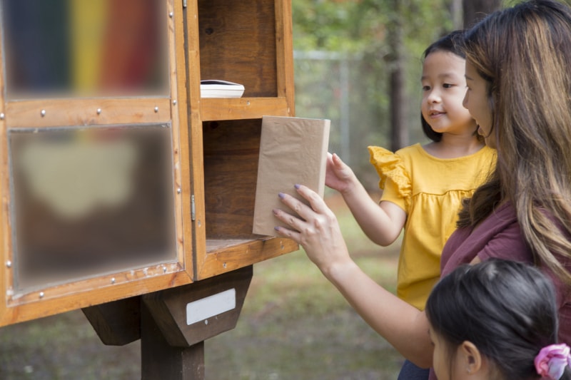 iStock-1352947054 opportunités de bénévolat famille échangeant des livres à la bibliothèque communautaire en plein air