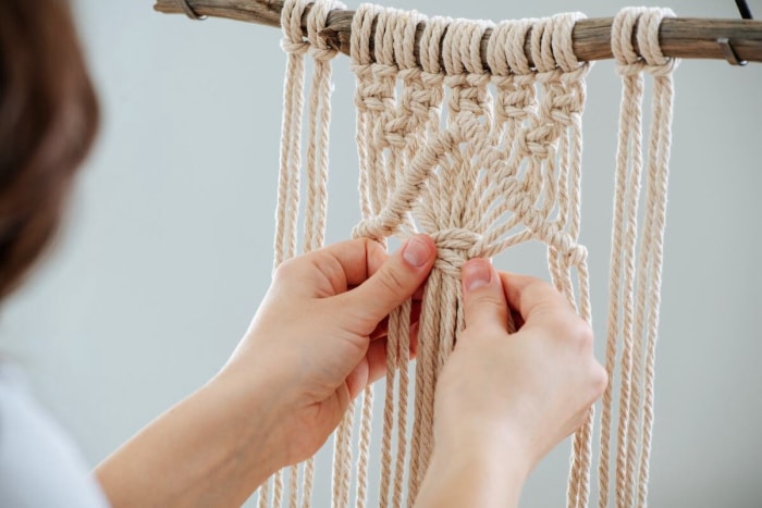 Femme apprenant à faire du macramé à la maison.