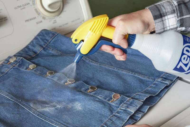 Une femme utilise un vaporisateur pour vaporiser une solution sur une jupe en jean.