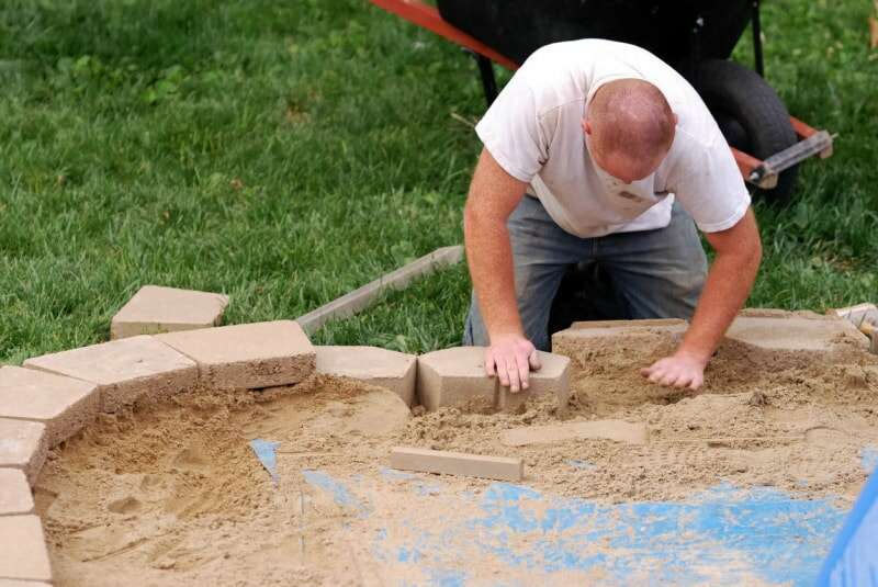 Un ouvrier est en train de construire un mur de soutènement.