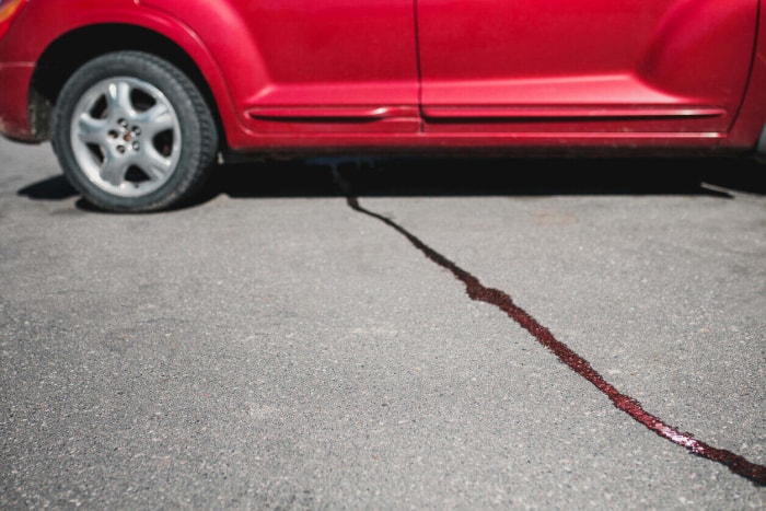 Un jet de liquide sur le trottoir sous la voiture - l'huile coule du moteur