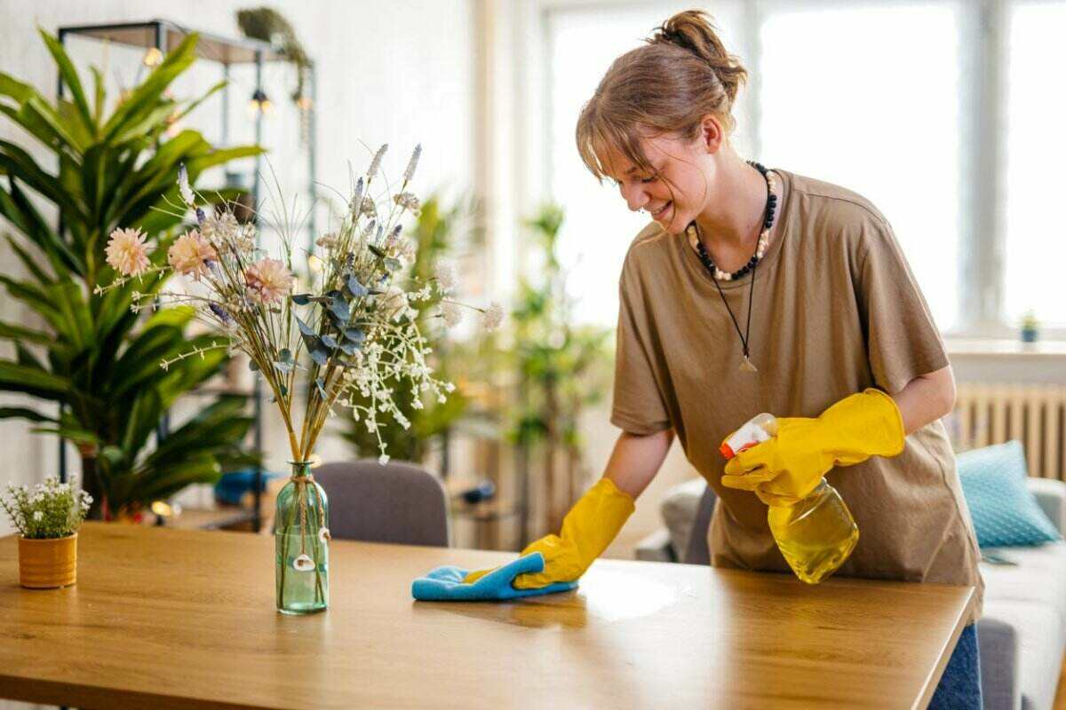 Vue d'une femme portant des gants de nettoyage jaunes essuyant une table. 