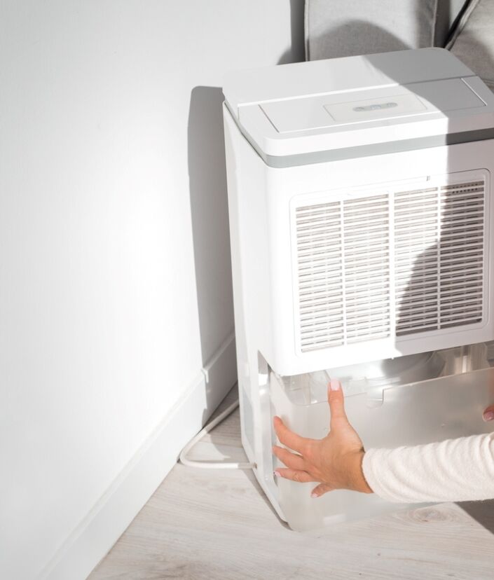 Femme tirant le récipient d'eau d'un humidificateur.