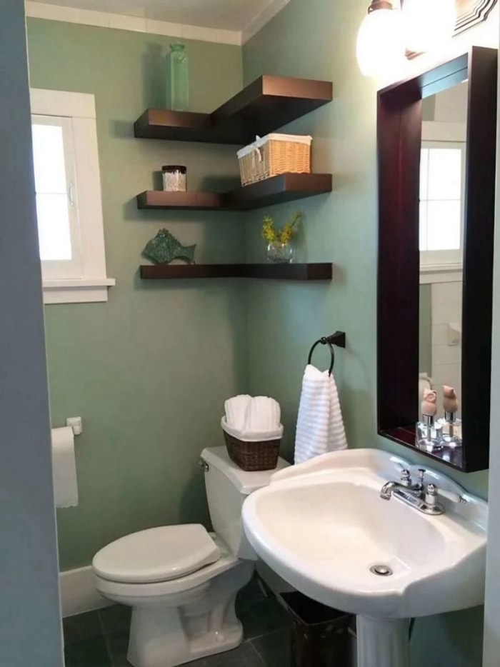 Une demi-salle de bain avec des murs verts terreux et des accents de bois foncé.