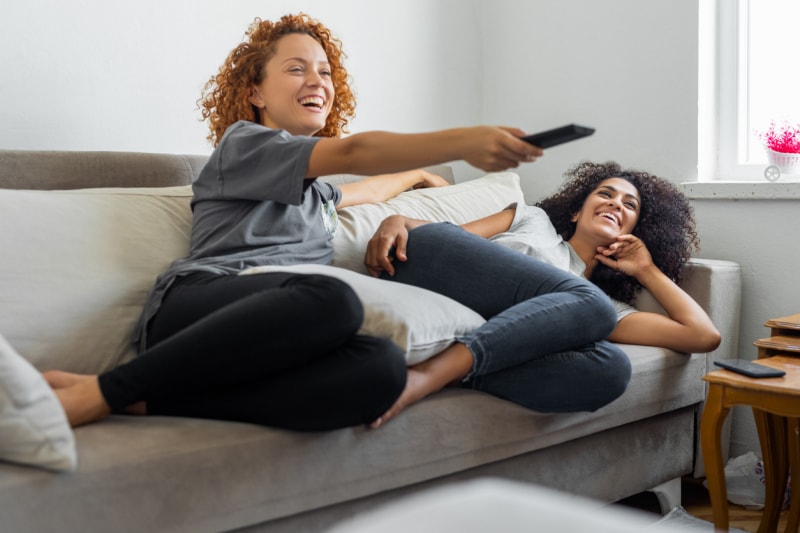 iStock-1350071405 productivité deux femmes regardant la télévision sur le canapé