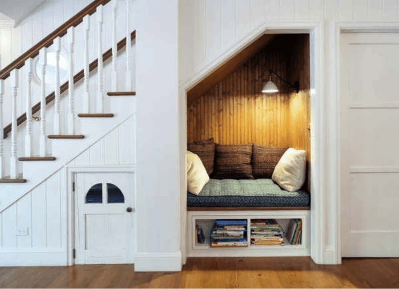 vue latérale d'un grand escalier blanc avec un coin en dessous avec des coussins et des panneaux de bois