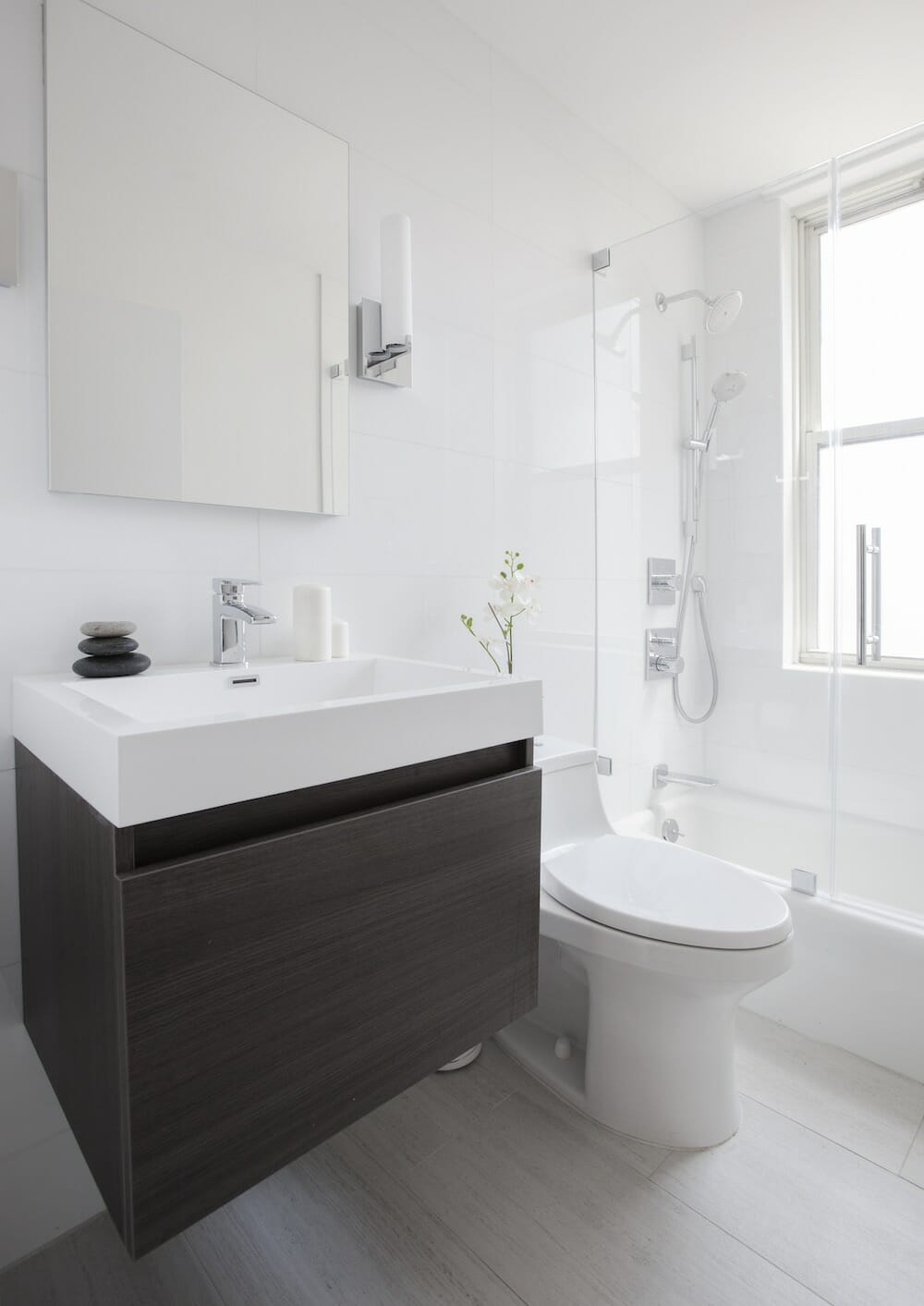 Une petite salle de bain blanche avec une vanité en bois sous un lavabo en porcelaine blanche.