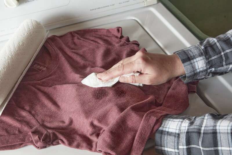 Une femme essuie une tache d'huile sur une chemise de l'intérieur et du devant.