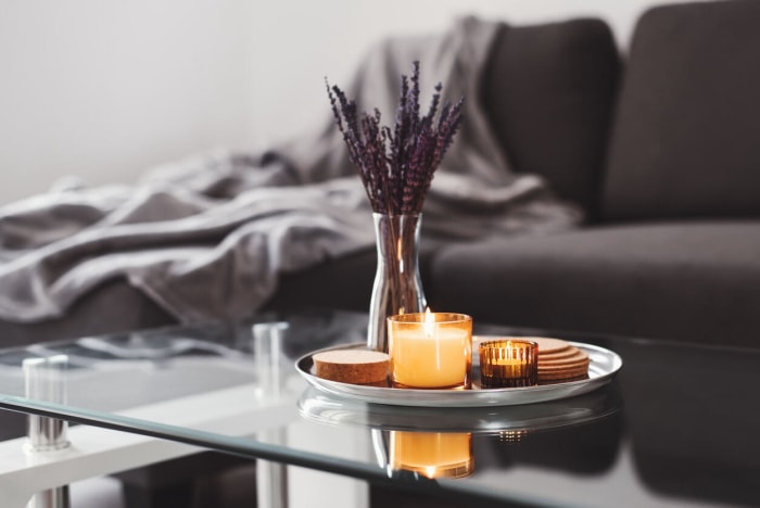 Bougie allumée sur un plateau avec d'autres décorations sur une table basse en verre.